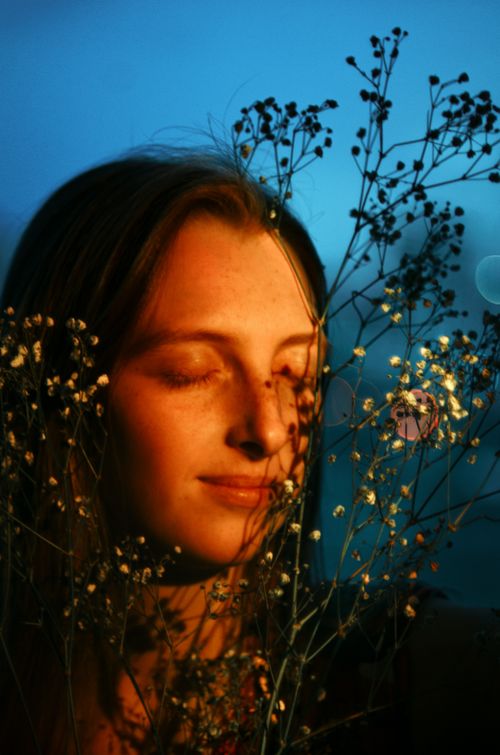 Free A young woman with eyes closed, enjoying the sunset amidst wildflowers. Warm, peaceful mood. Stock Photo