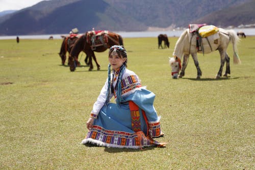Woman Sitting in Traditional Clothing on Grassland