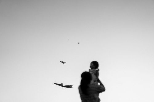 Free Silhouette of a mother and child watching kites soar in the sky. Stock Photo