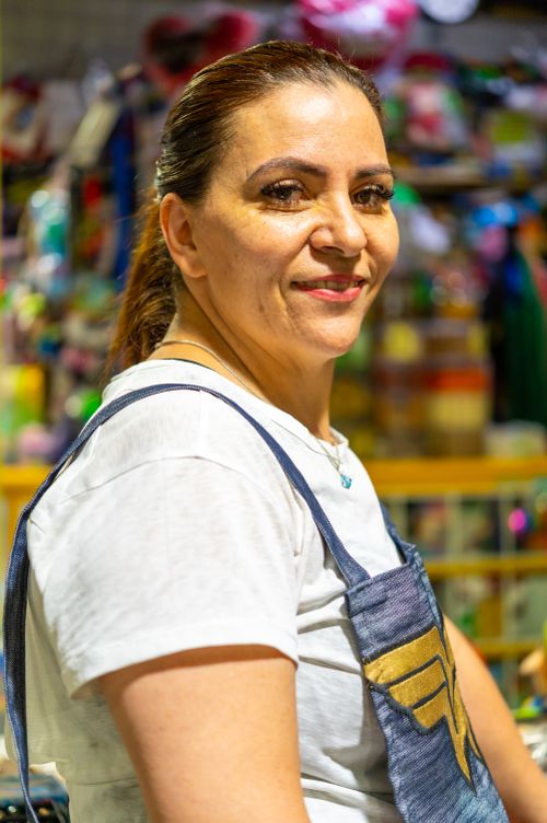 Free A cheerful woman wearing overalls and a t-shirt, smiling in a bustling market in Ciudad de México. Stock Photo