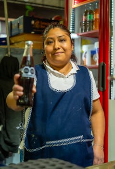 Smiling woman with soda bottle at a food stall in Mexico City. Vibrant and inviting portrait.