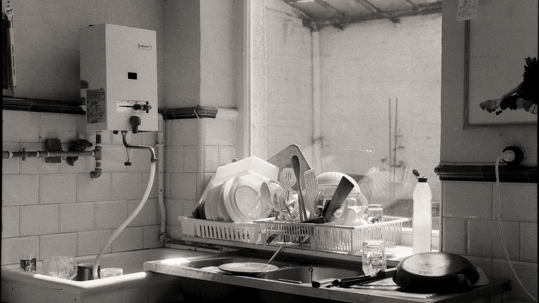 A kitchen sink filled with dishes beside a window