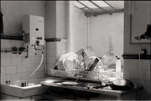 Free Black and white image of a kitchen sink filled with dishes and cutlery by the window. Stock Photo