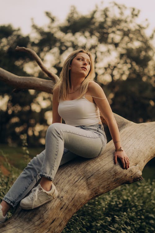 Blonde Woman Sitting and Posing on Tree Trunk