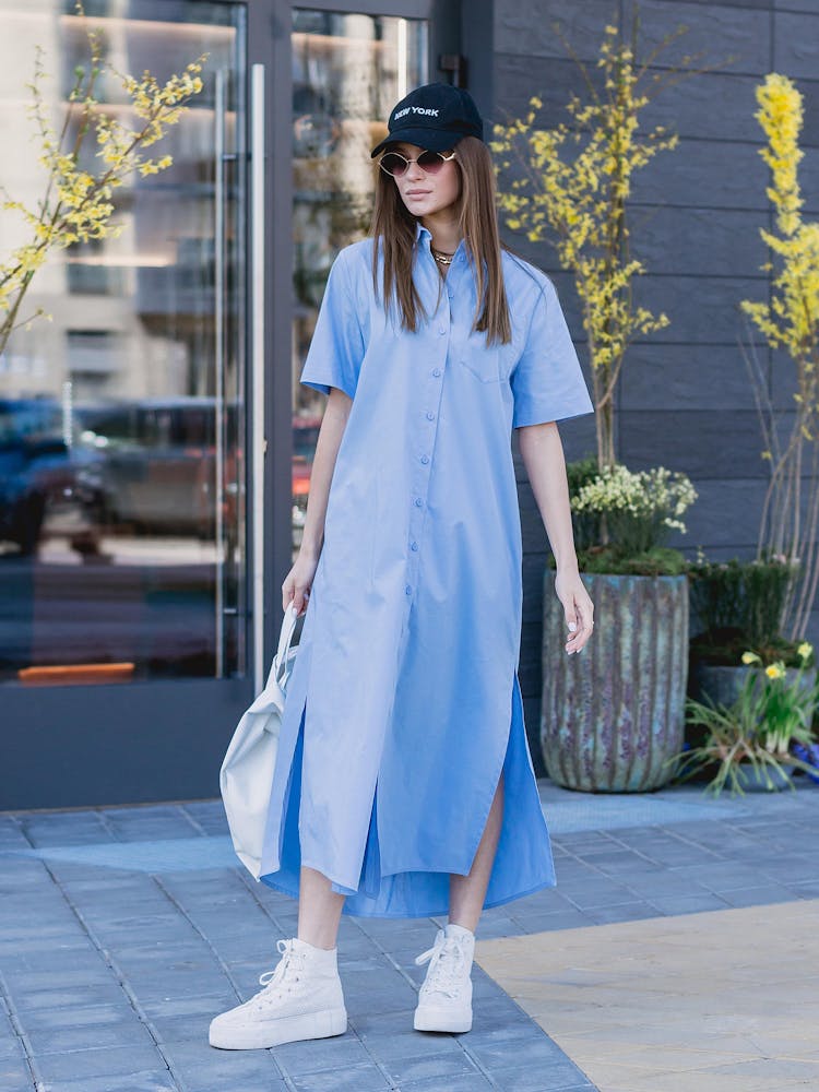 Woman In Blue Dress Standing By Building Entrance