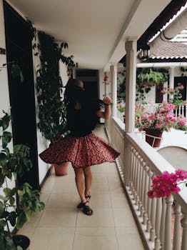 一位时尚女士在风景如画的哥伦比亚阳台上，穿着花卉裙子旋转