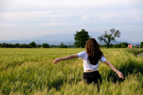 Back View of a Woman Standing on a Field with Spread Arms 