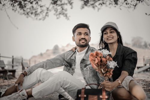 Free Young couple enjoying a romantic picnic outdoors with a bouquet of flowers. Stock Photo