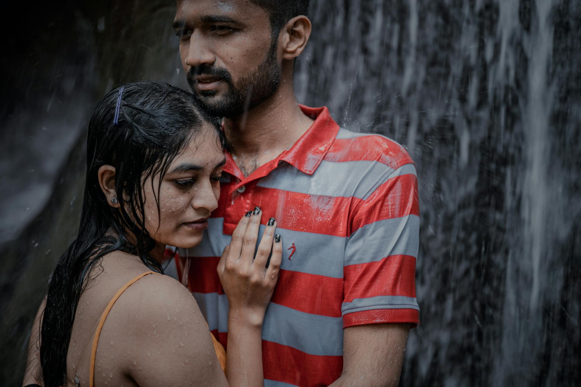 Wet Couple Standing under Waterfall