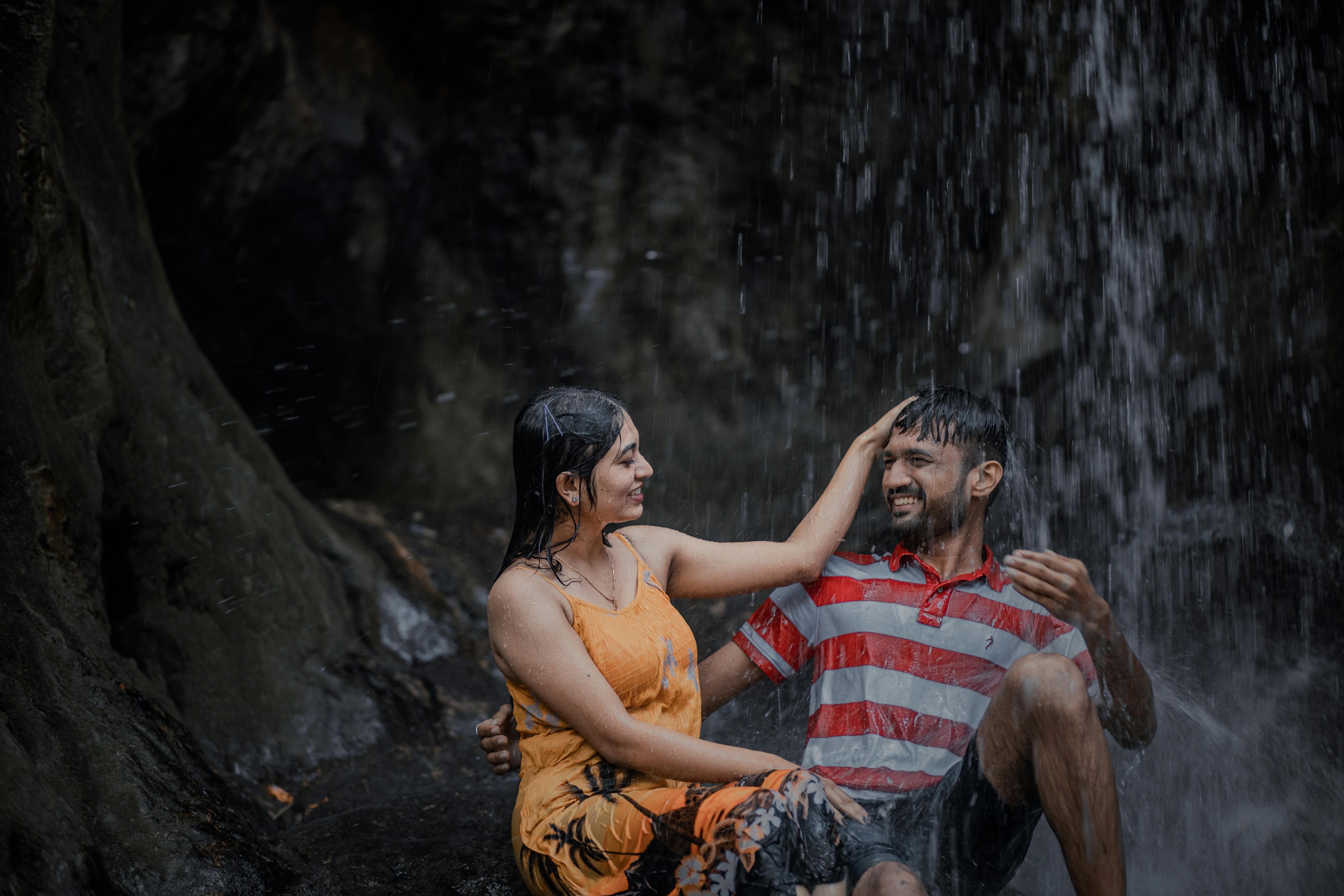 Wet Couple Sitting under Waterfall · Free Stock Photo