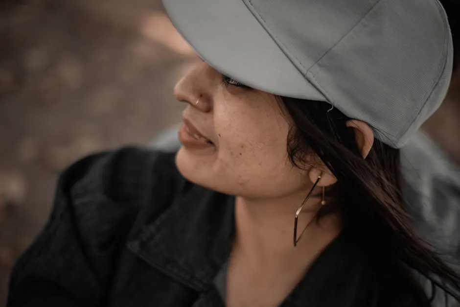 Femme de profil portant une casquette grise unie, visière tournée vers l'arrière