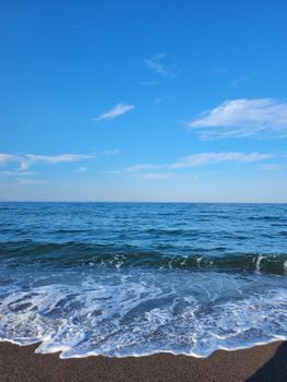 Calm waves gently hitting the sandy beach under a bright blue sky