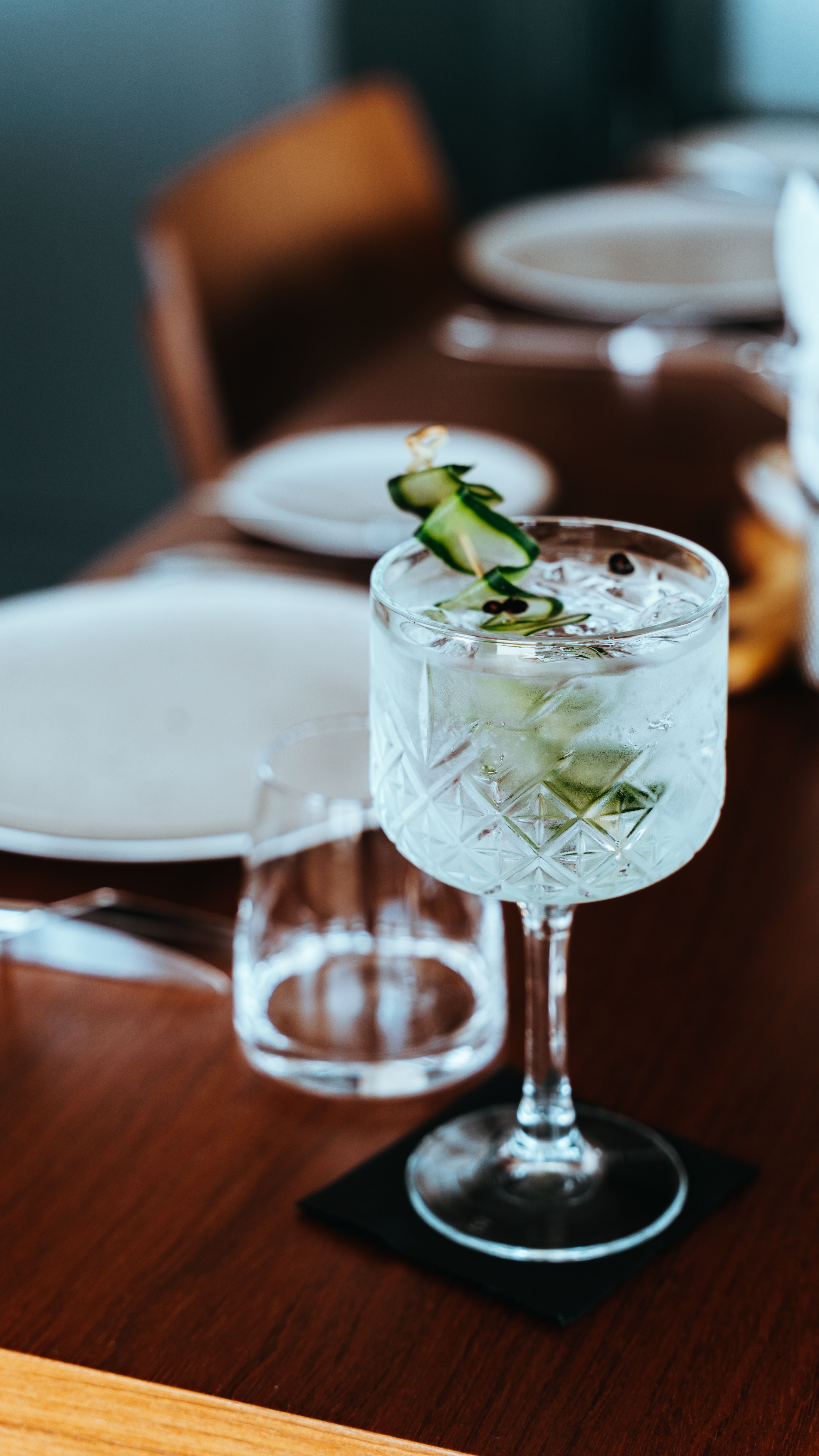 Chic cocktail in crystal glass with cucumber garnish, perfect for social gatherings.