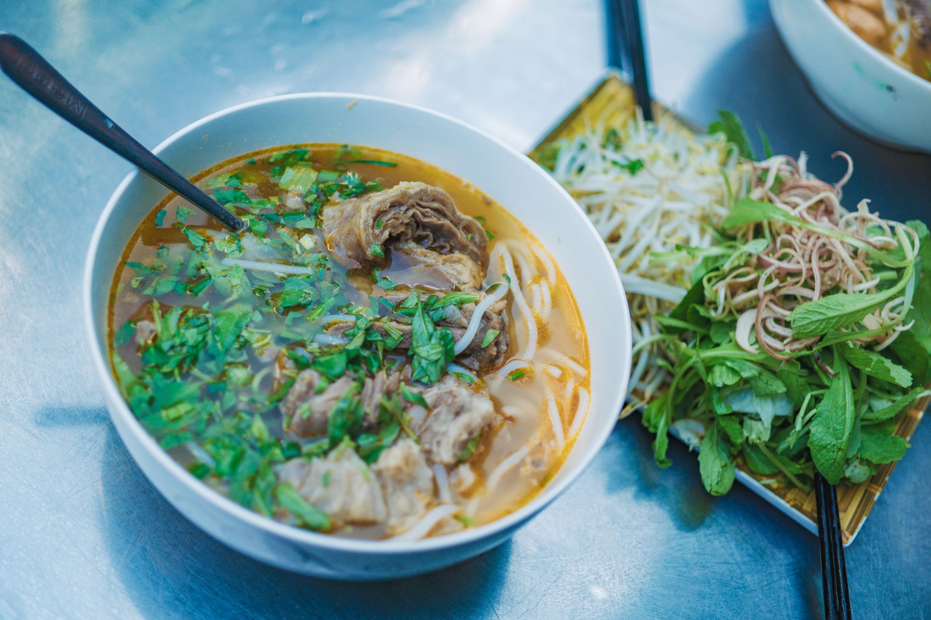 A mouthwatering bowl of Vietnamese pho with fresh herbs and side salad, perfect for food lovers.