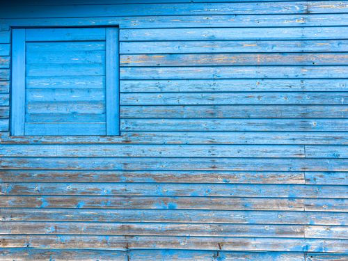 Free Close-up of a weathered blue wooden building wall with peeling paint and natural texture. Stock Photo