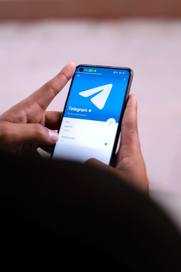 Hands holding a smartphone with the Telegram app open on the screen