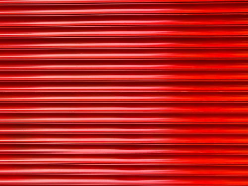 Free Close-up of a vibrant red metal sheet with horizontal pattern, ideal for backgrounds. Stock Photo