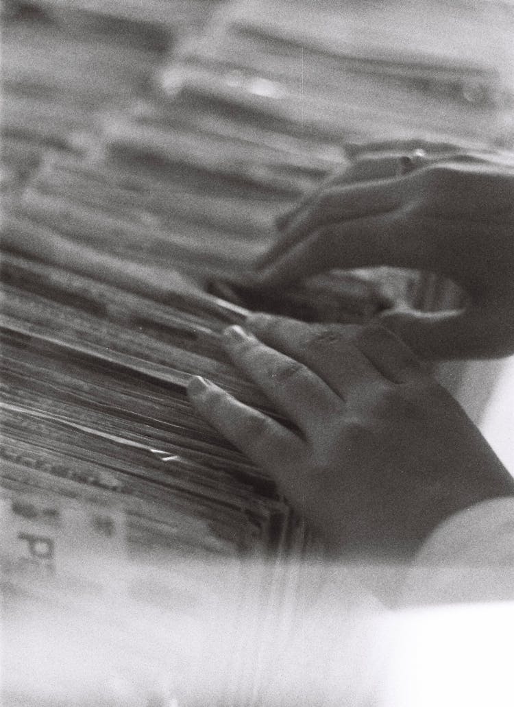 Close-up Of A Person Looking Through A Pile Of Magazines