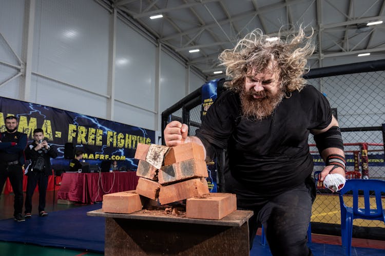 Man Breaking A Pile Of Bricks With His Fist