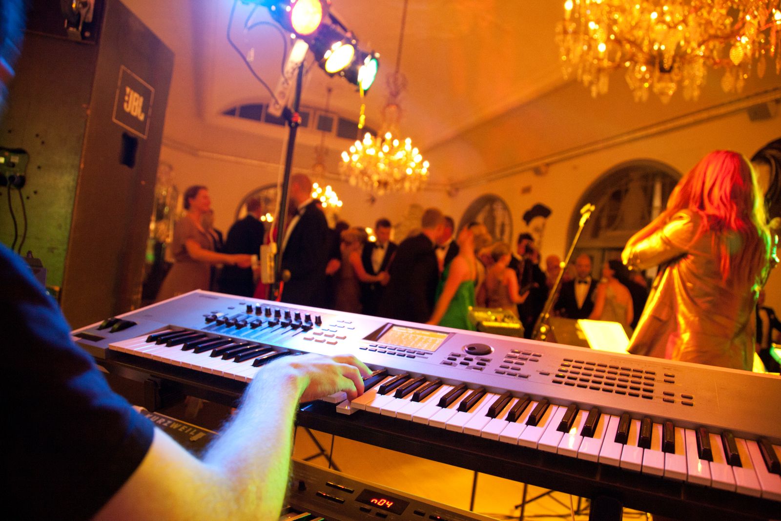 A keyboard player performing while guests dance at an evening celebration