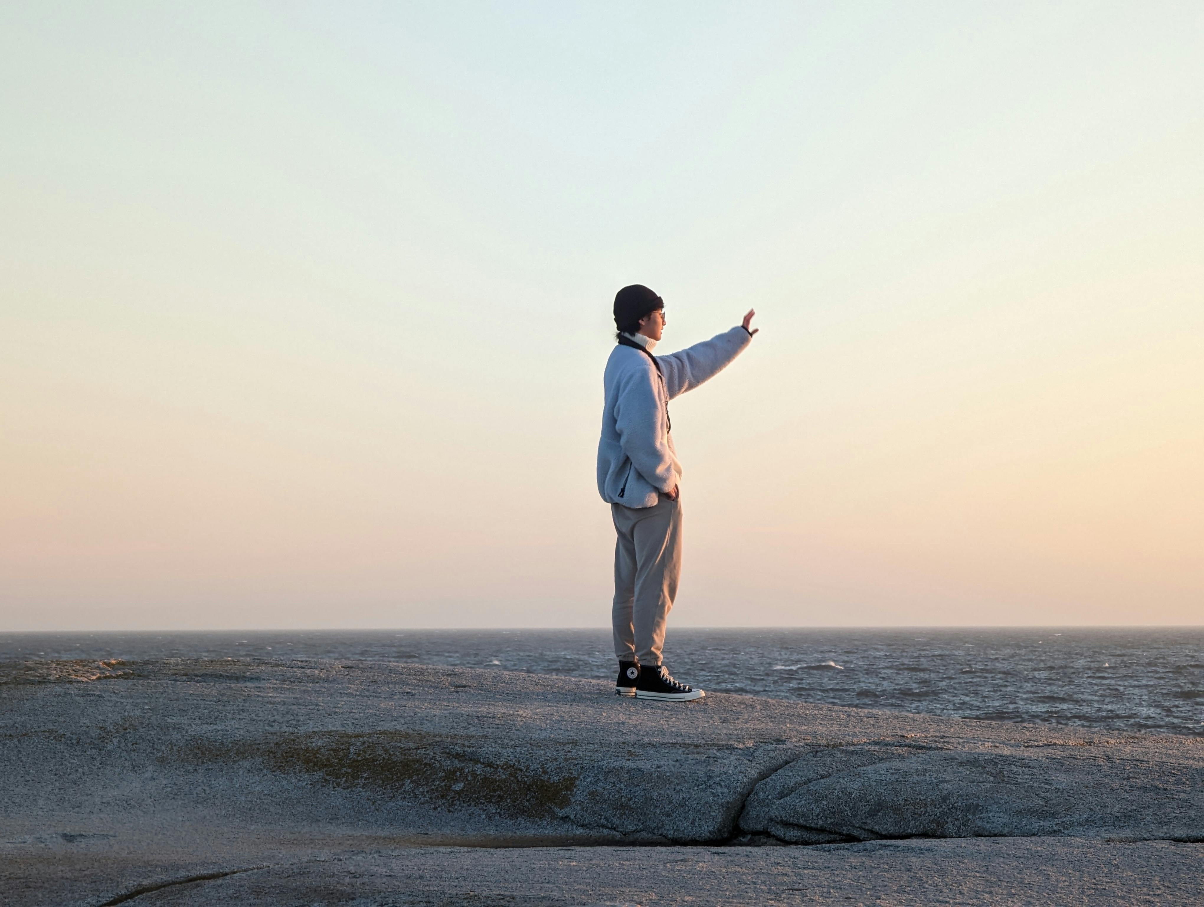 A serene moment at Peggys Cove with a person gazing into the sunset view.