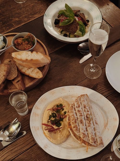 Free Enjoy a stylish meal featuring hummus, bread, and fine dining elements on a rustic wooden table. Stock Photo