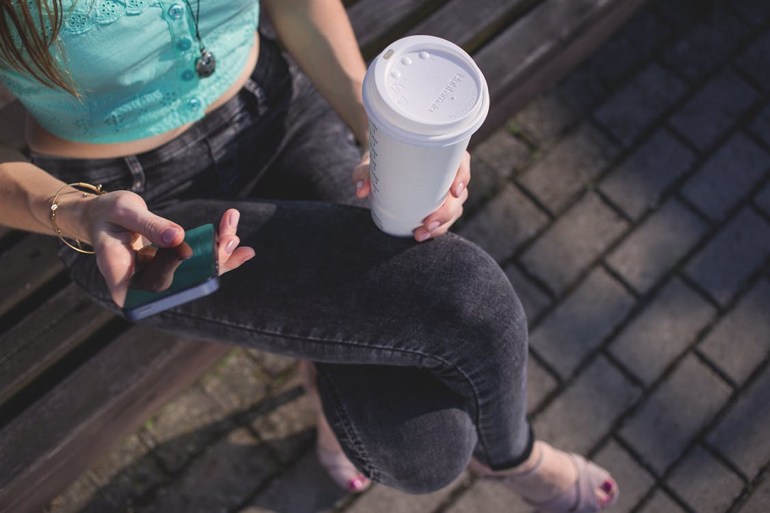 Free Woman Holding White Disposable Cup and Smartphone Stock Photo