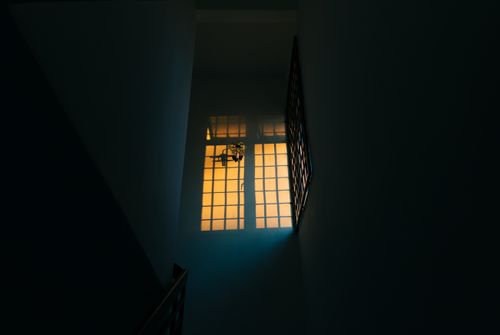 Free A dimly lit hallway with a warm glow from the window, creating a dramatic contrast. Stock Photo