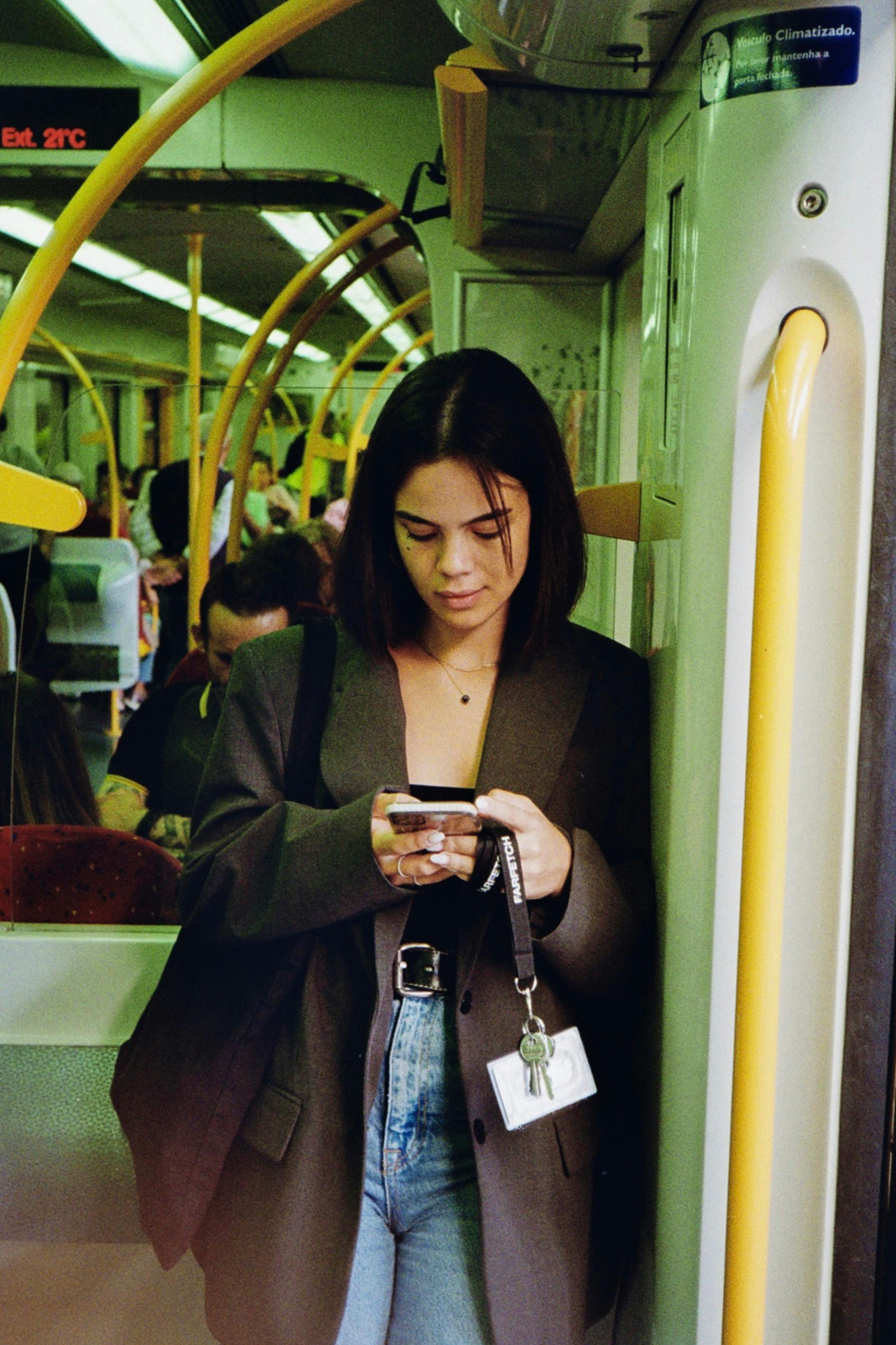 Stylish young woman using her phone on a train in Porto, captured in candid moment.