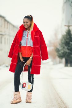 白雪皑皑的街道上，一位身穿鲜艳红色外套的时尚女子正微笑着