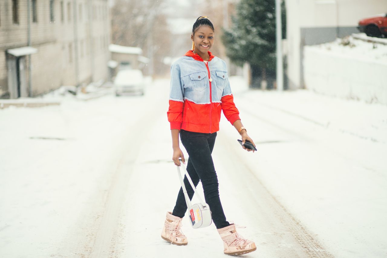 a woman walking down a snowy street in winter boots