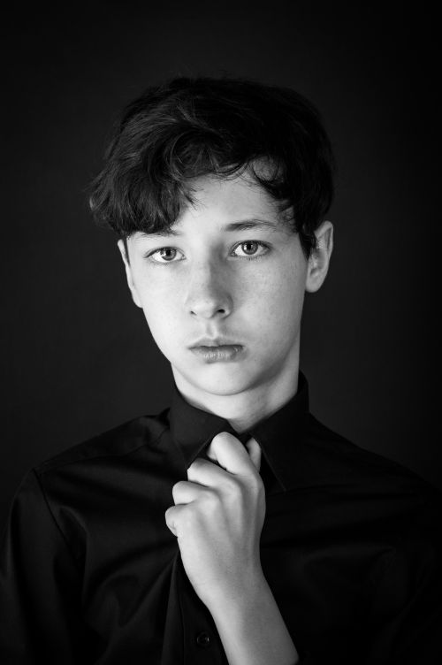 Free Thoughtful black and white portrait of a young boy wearing a shirt, captured in a studio setting. Stock Photo