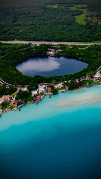 Stunning aerial shot of Bacalar Lagoon, showcasing vibrant blue waters and lush greenery in Quintana Roo, Mexico.