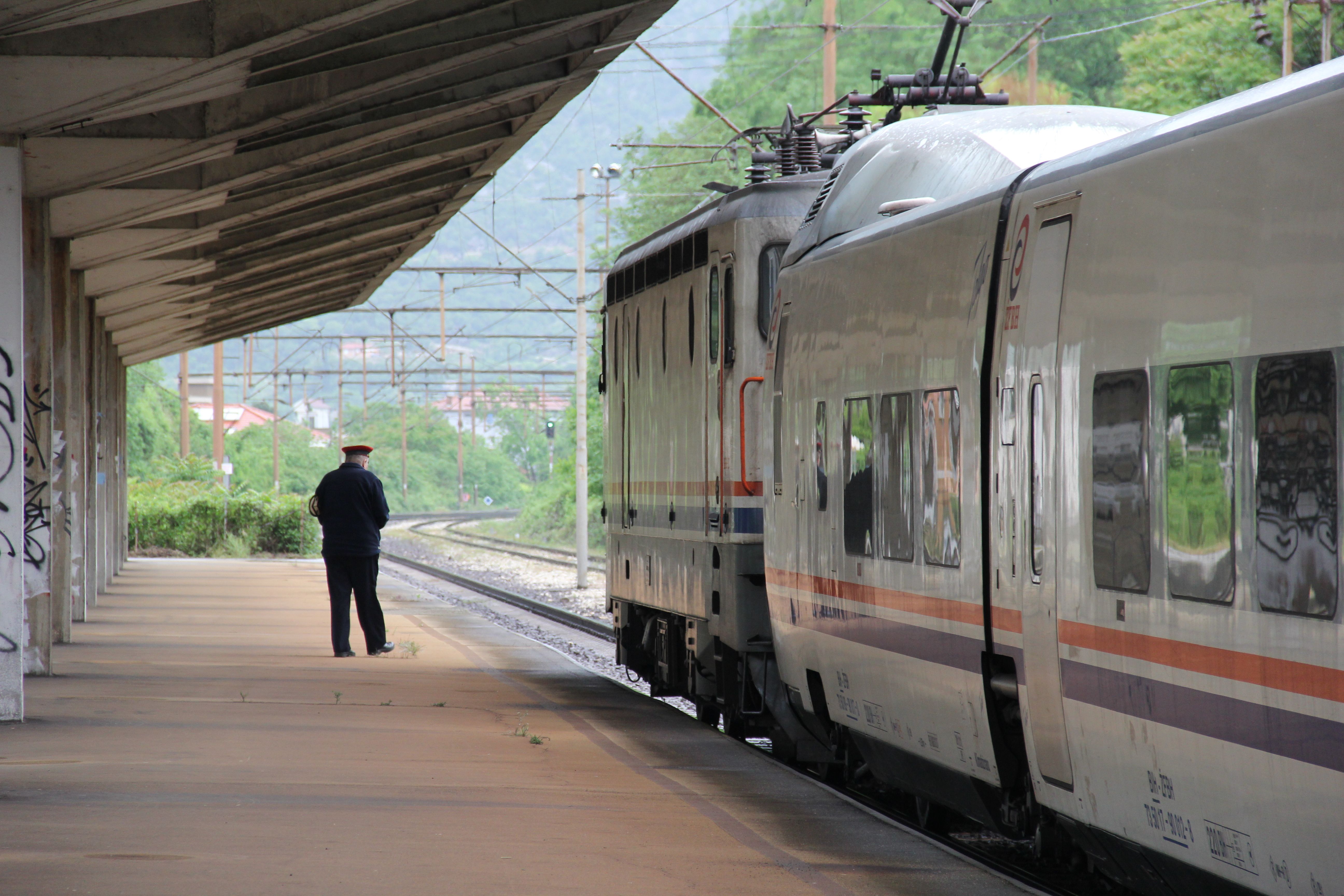 Bir tren kondüktörü istasyonda trenin yanında duruyor