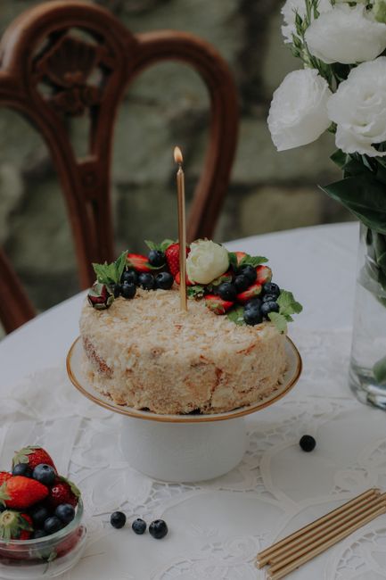 A homemade cake topped with fresh berries and a lit candle, perfect for celebrations.