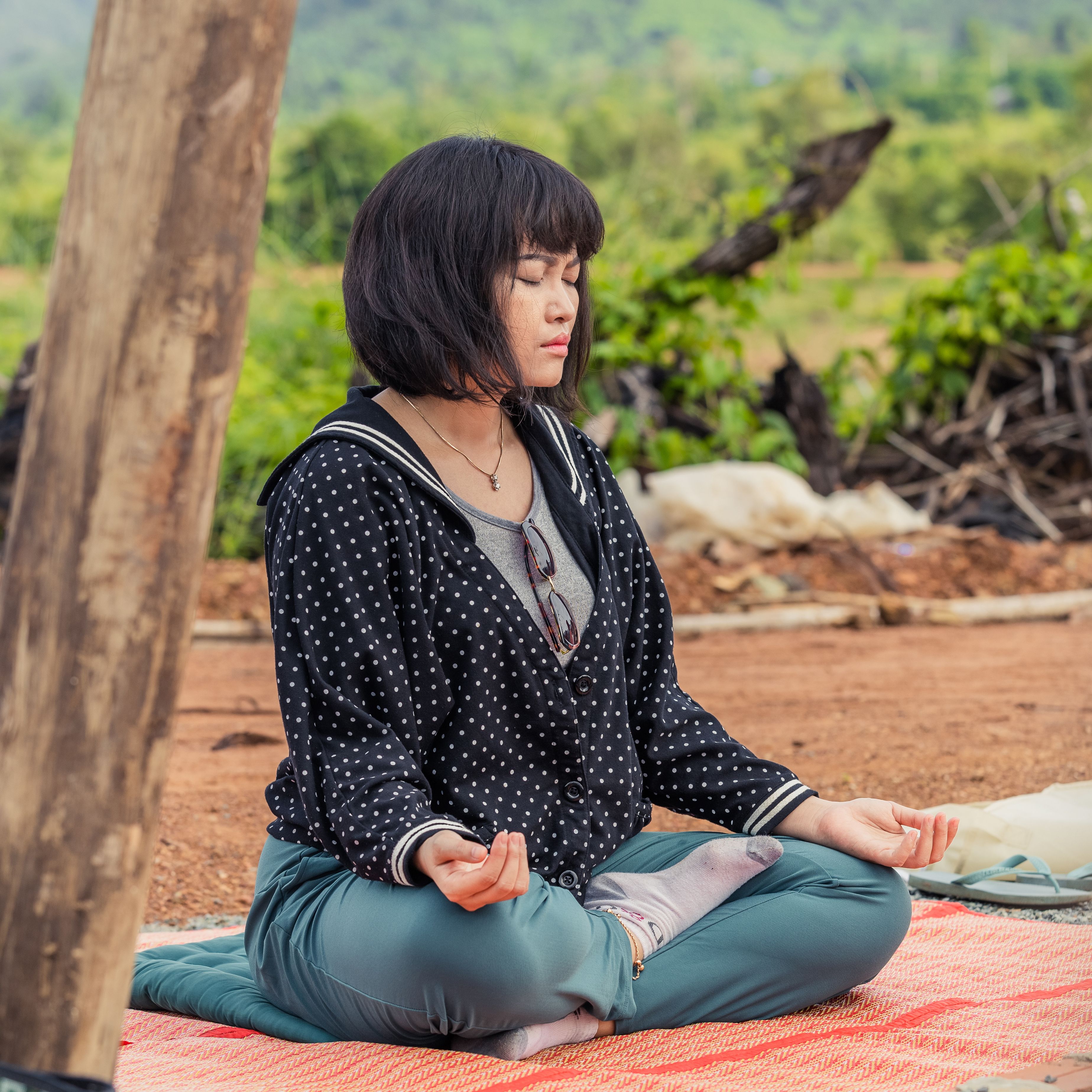 Woman meditating on a mat outdoors — photo by Viriya Lim on Pexels