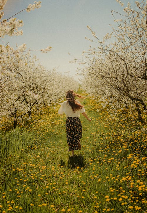 Woman Running in Blossoming Orchard