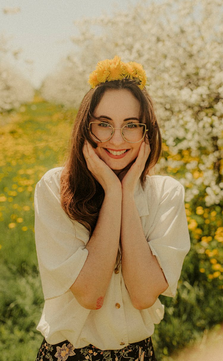 Smiling Woman With Flowers On Head Standing In Blossoming Orchard