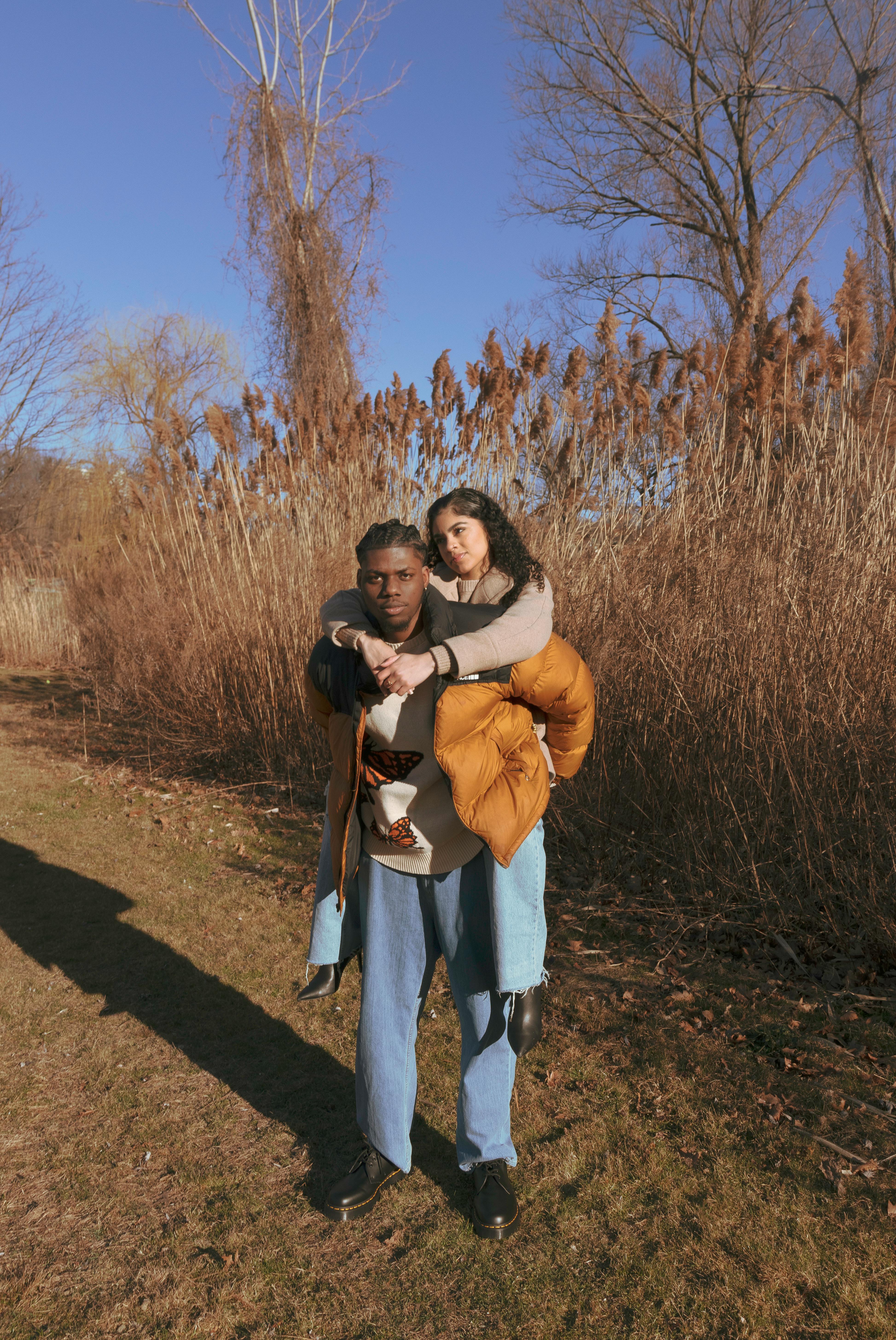A loving couple shares a piggyback ride in a golden autumn setting, showcasing warmth and togetherness.