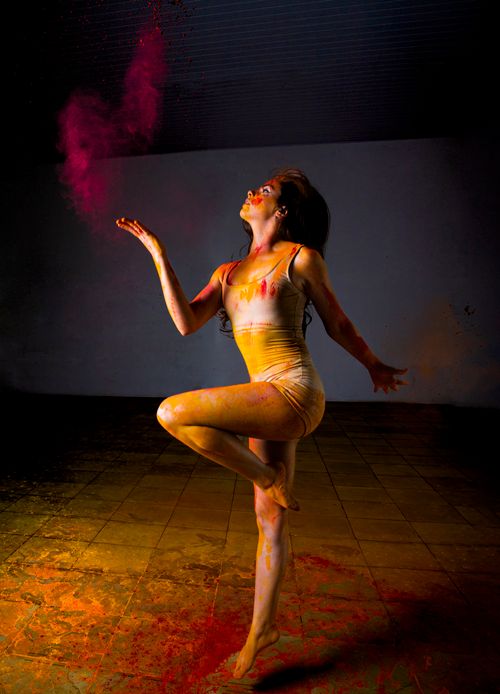 Free Woman performing a dance with vibrant powder creating a striking artistic effect. Stock Photo
