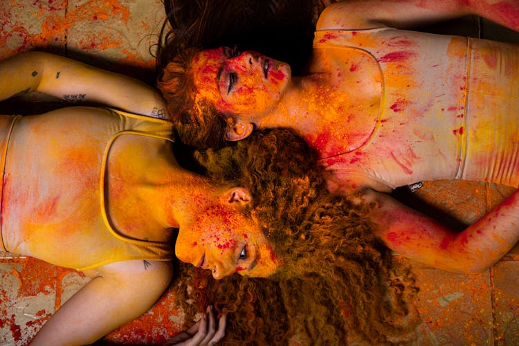 Women Lying Down With Colorful Paint On Bodies And Clothes