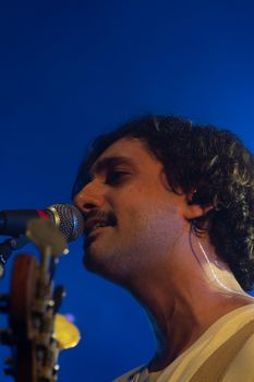 Close-up of a male singer passionately performing on stage with a microphone and guitar.