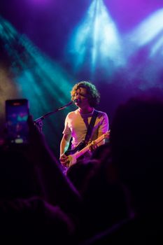 Guitarist performing on stage under vibrant lights during a concert.