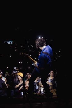 Guitarist on stage performing live while audience captures the moment.