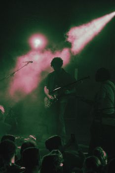 Energetic live concert performance featuring electric guitarists in vibrant stage lighting.