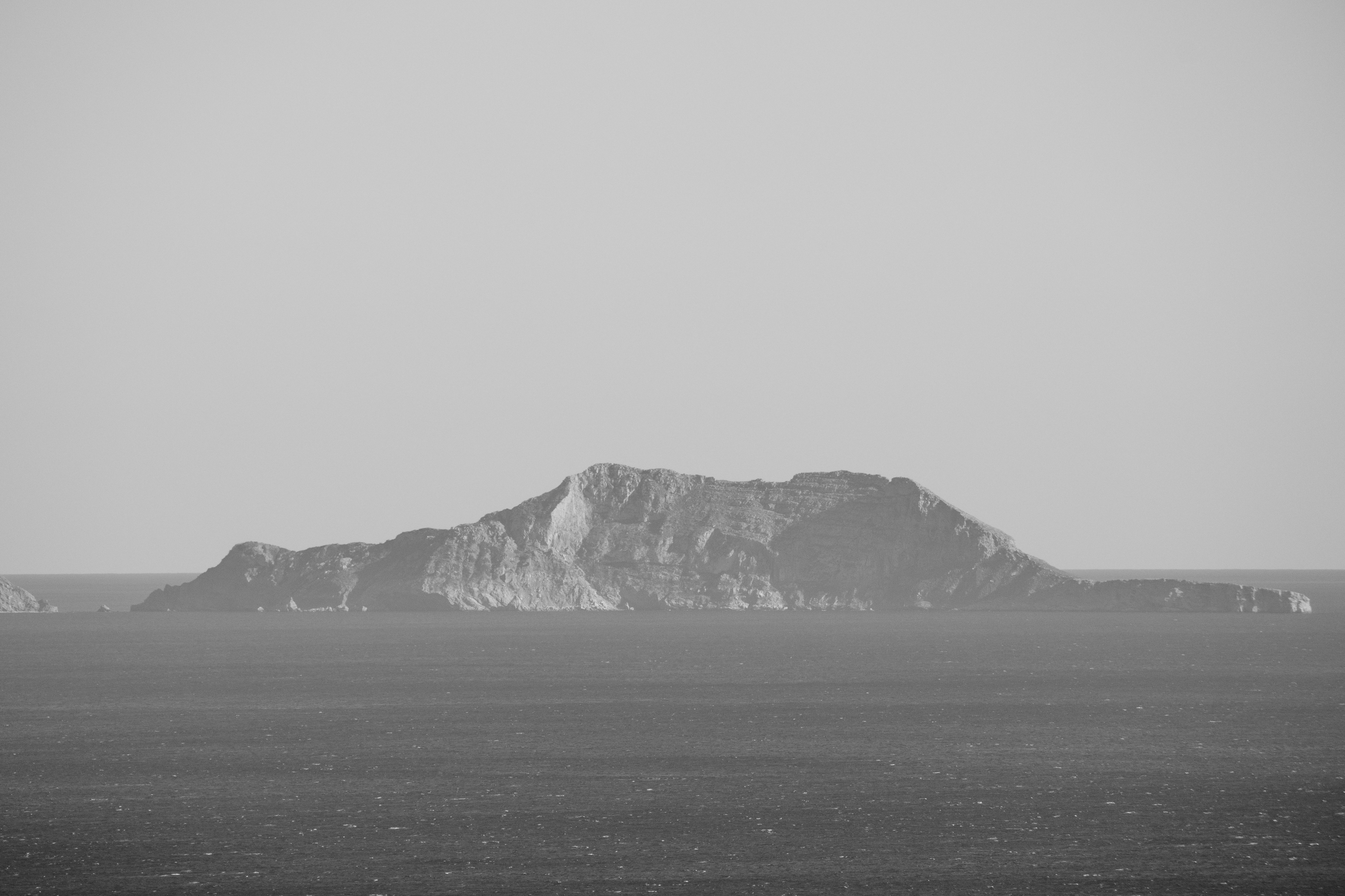 Rocky Island on Sea Shore in Black and White · Free Stock Photo