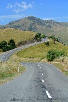 Winding road through green hills in Canterbury, New Zealand on a clear day.