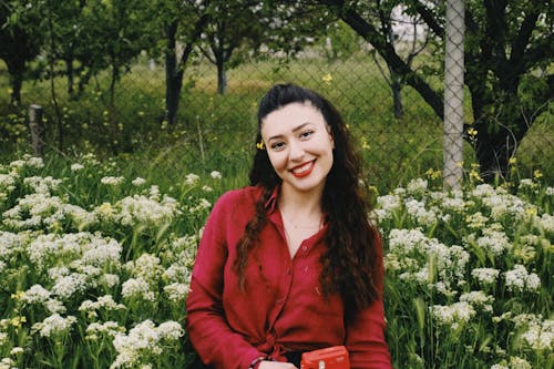 Smiling Woman Sitting among Flowers