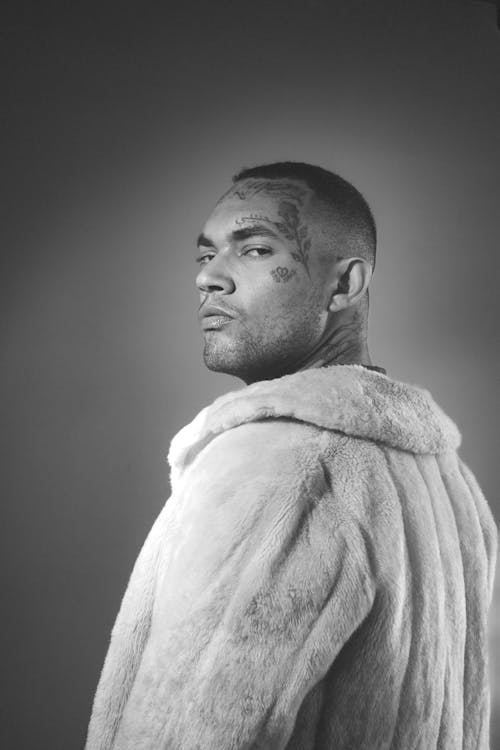 Black and White Photo of Man with Tattooed Face Wearing Fur Coat