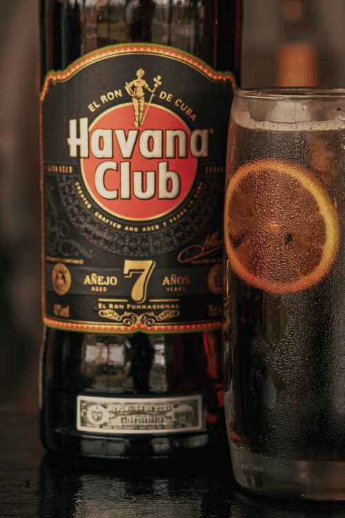 Free Close-up of Havana Club rum bottle and cocktail glass with orange slice, perfect for beverage themes. Stock Photo